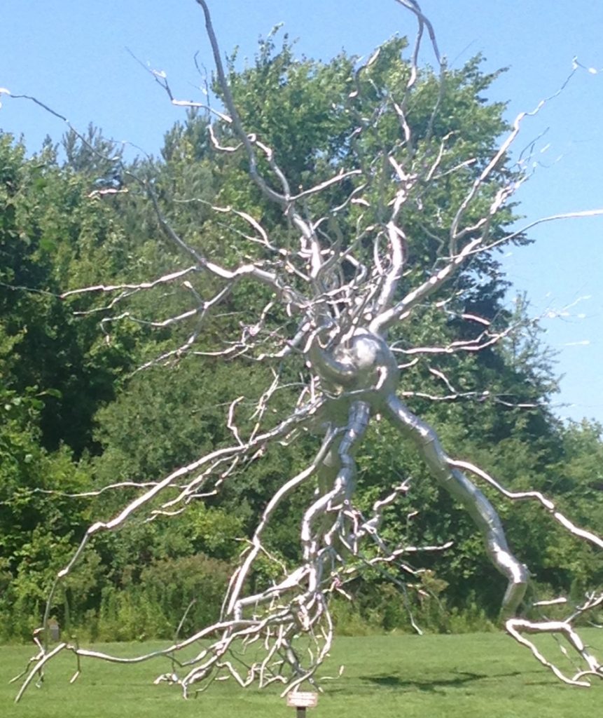 bright metal sculpture of a ball with roots growing out of it all around