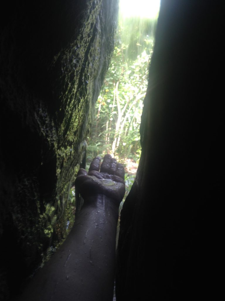 my hand, reaching through a crack in a rock towards a waterfall