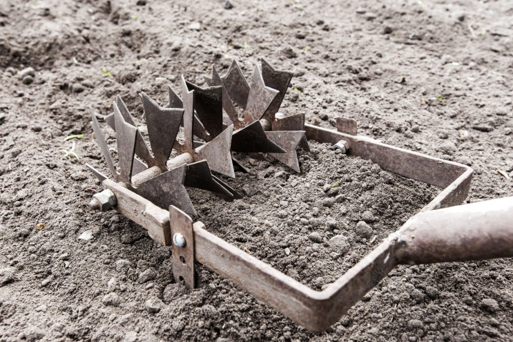 An image of a hand plow scraping over hard ground.